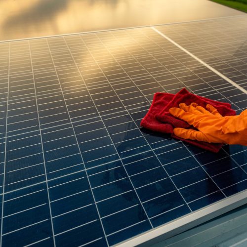 Man cleaning solar panel on roof. Solar panel or photovoltaic module maintenance. Sustainable resource and renewable energy for go green concept.  Solar power for green energy. Technology for future.